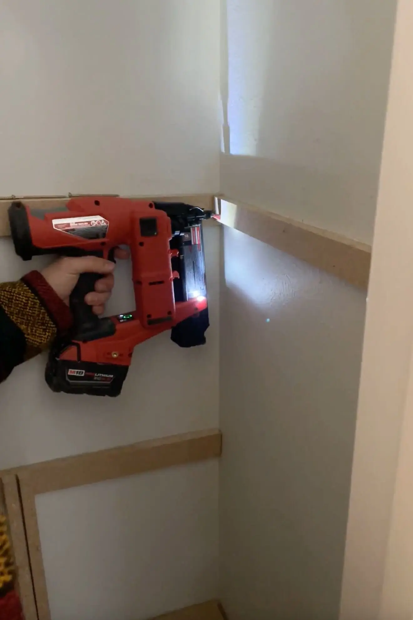 DIY closet shelves in progress: installing wooden shelf supports with a red cordless nail gun for a custom storage upgrade.